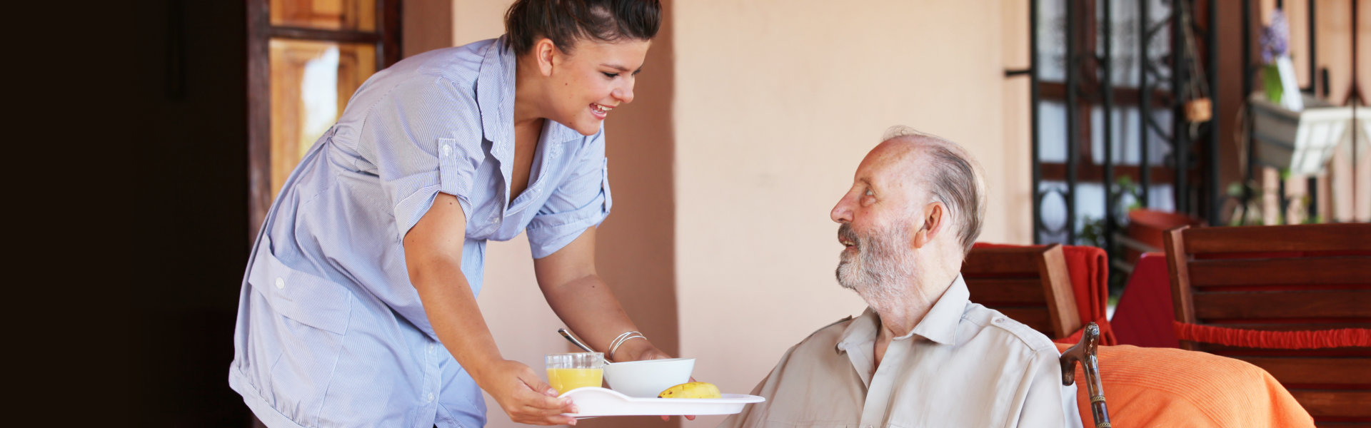 caregiver serving food to an elderly man